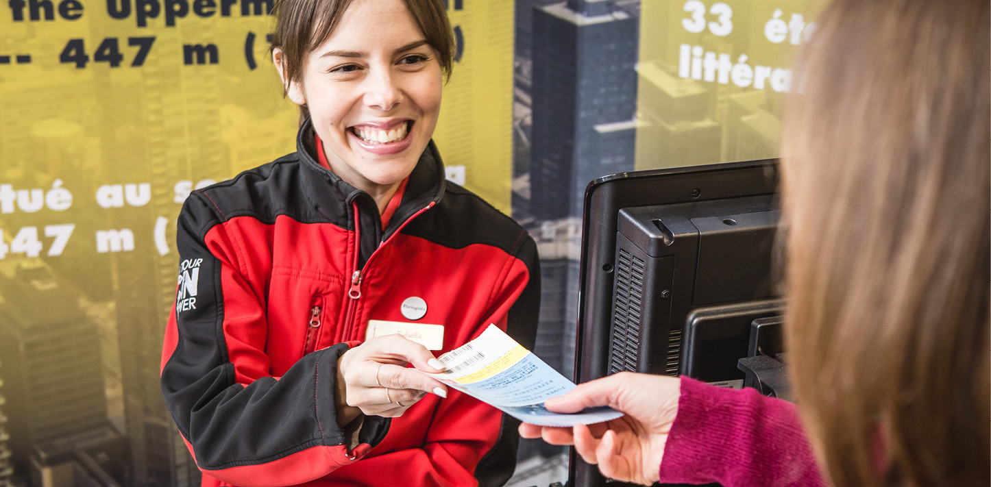 Un employé de la Tour CN sourit en donnant un billet à un visiteur.