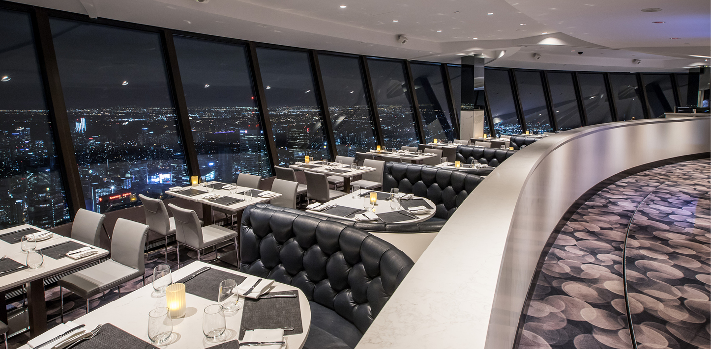 Le restaurant dispose de tables et de chaises le long de la fenêtre et de cabines de l'autre côté de l'allée. La vue donne sur Toronto la nuit