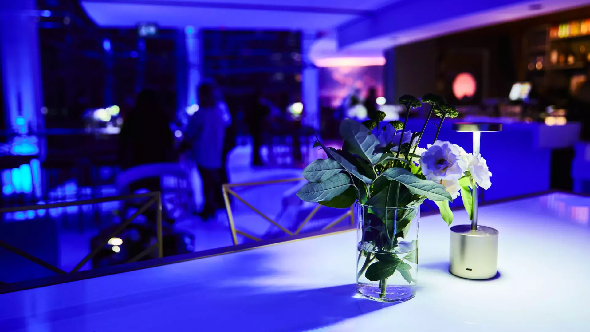 vue d'un vase de fleurs et d'une lampe sur une table lors d'un événement à la Tour CN. L'atmosphère est sombre avec une teinte violette.