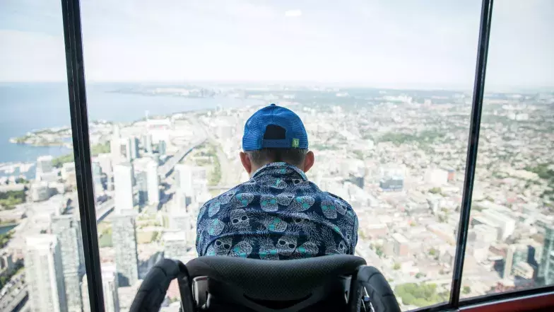 personne en fauteuil roulant regardant par la fenêtre à la Tour CN