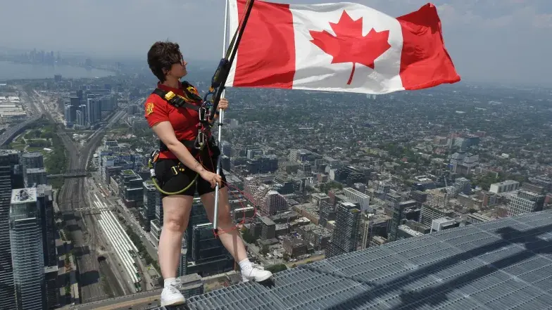 Jeune personne debout sur l'Haut-da Cieux tenant un drapeau canadien