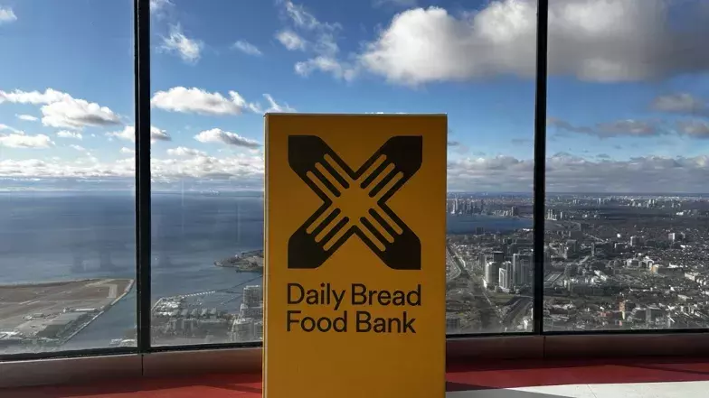 Boîte à dons jaune de la banque alimentaire Daily Bread sur le niveau d'observation principal de la Tour CN, avec vue sur l'ouest de Toronto.