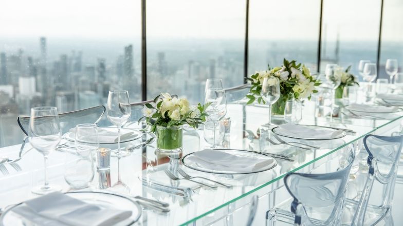 Table et chaises en plexiglas transparent, élégamment disposées pour le dîner, placées le long des fenêtres.