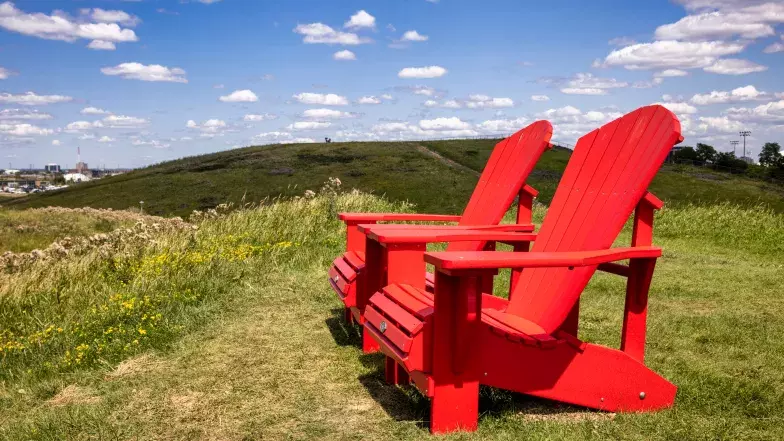 Deux chaises Adirondack rouges sur une pelouse verte du Parc Downsview.