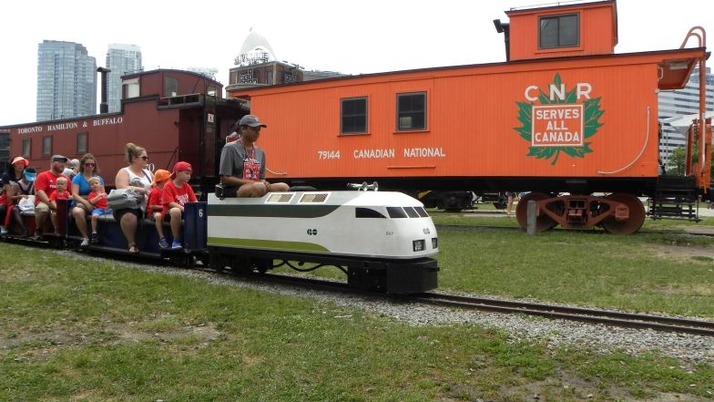 Un train miniature, avec un groupe d'adultes et d'enfants assis dans le train.