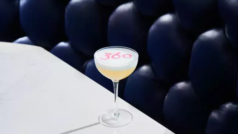 Gros plan sur un cocktail dans un petit verre coupe au restaurant 360. Le logo 360 est inscrit au pochoir sur le cocktail.