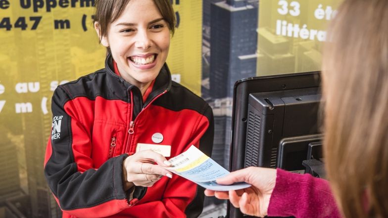 Un employé de la Tour CN sourit en donnant un billet à un visiteur.