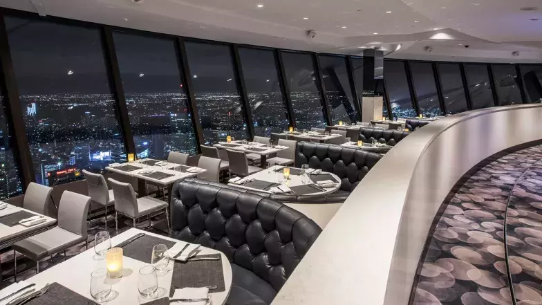 Le restaurant dispose de tables et de chaises le long de la fenêtre et de cabines de l'autre côté de l'allée. La vue donne sur Toronto la nuit