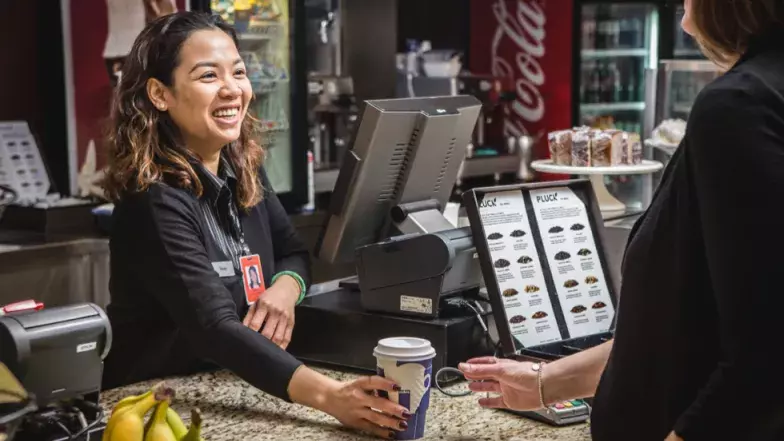 Employée accueillant un client chez Le Café