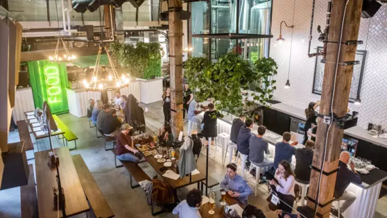 Vue en plongée des personnes assises au bar, tables de style bar.