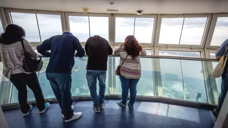 4 personnes appuyées sur la balustrade dans la Nacelle en regardant vers le bas.