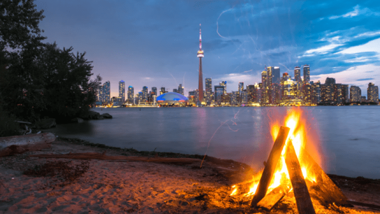 Un feu de joie à l'avant, le lac. La tour du CN et l'horizon de la ville de Toronto en arrière-plan.
