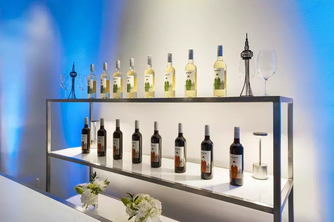 Detailed view of a bar serving area displaying wine bottles and vases with flowers on a shelving unit. 
