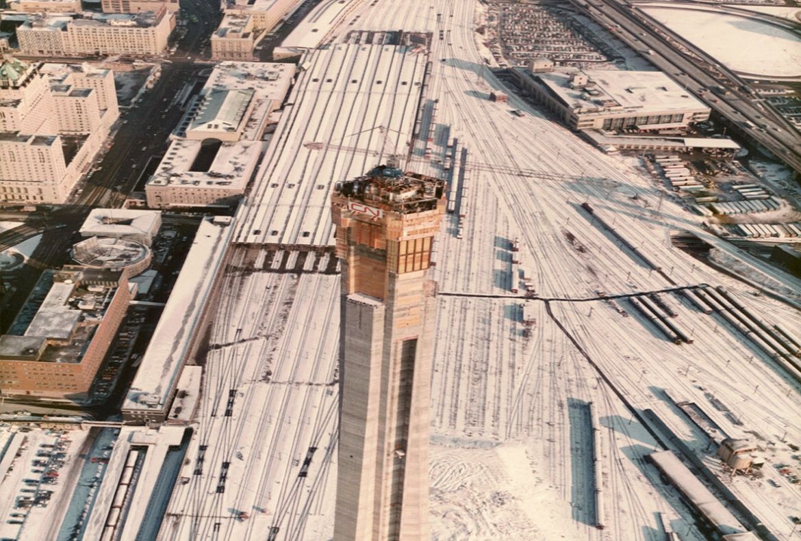 Une vue aérienne du chantier de construction de la Tour CN en direction est et les gares de triage avoisinantes recouvertes de neige, en décembre 1973.