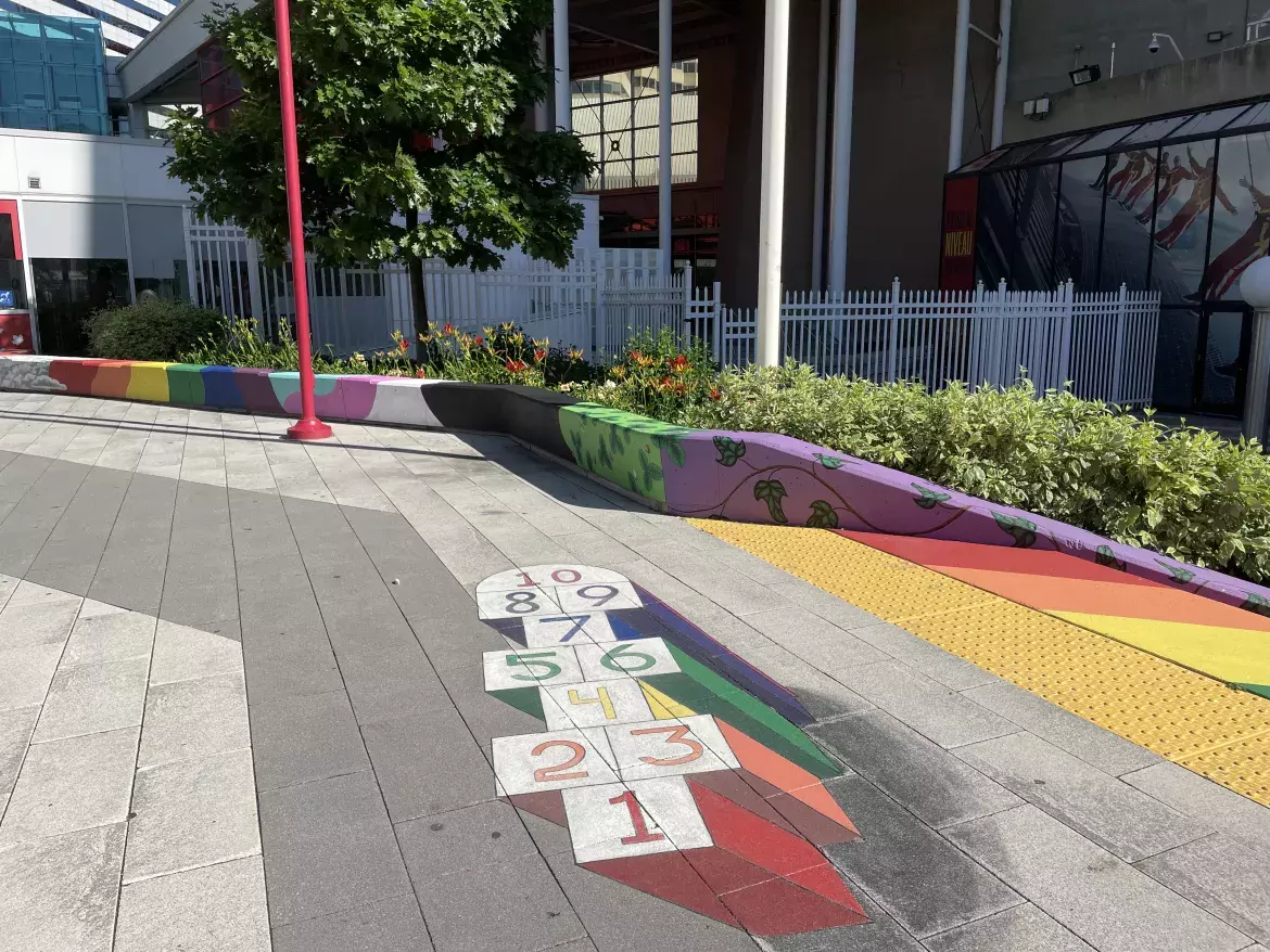 Peinture de marelle colorée sur la Place de la Société immobilière du Canada. En arrière-plan, d'autres peintures de plantes et d'arcs-en-ciel.