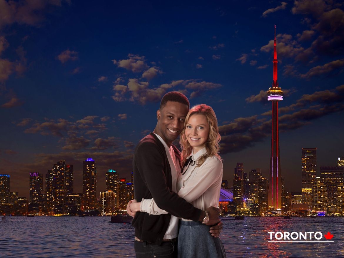 A couple smiling in front of Toronto skyline, capturing a beautiful moment together.