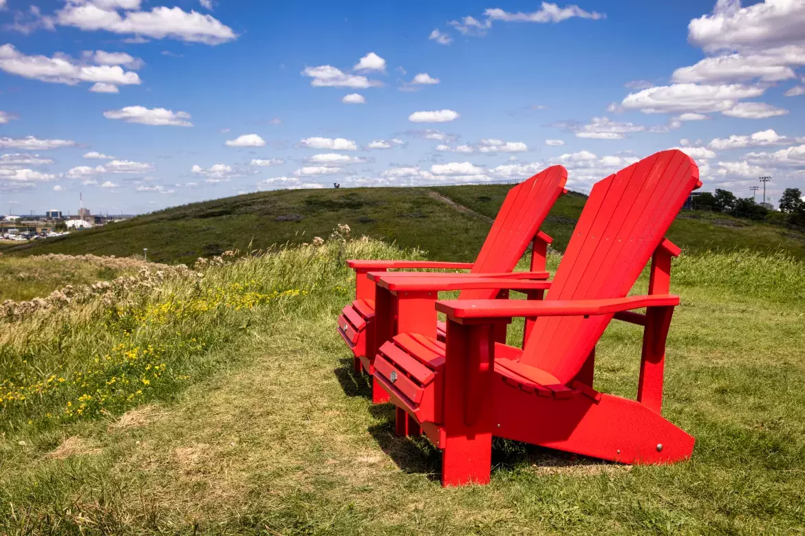 Deux chaises Adirondack rouges sur une pelouse verte du Parc Downsview.
